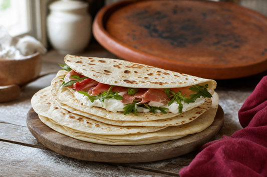Piadine romagnole appena cotte, una piegata con prosciutto crudo, squacquerone e rucola