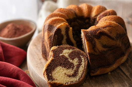 Ciambella variegata al cacao e vaniglia con una fetta tagliata che mostra l'interno marmorizzato
